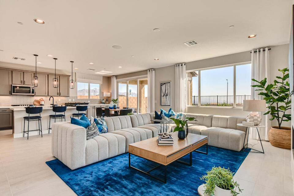 A large living room with a blue rug and a large window.