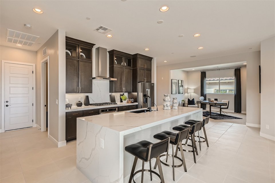 A kitchen with a bar and chairs.