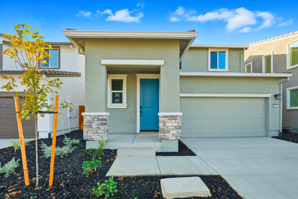 A house with a garage and a tree in the front.