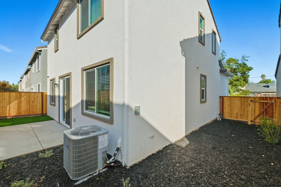 A white house with a trash can in front of it.