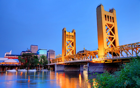 A bridge over a river with buildings in the background.