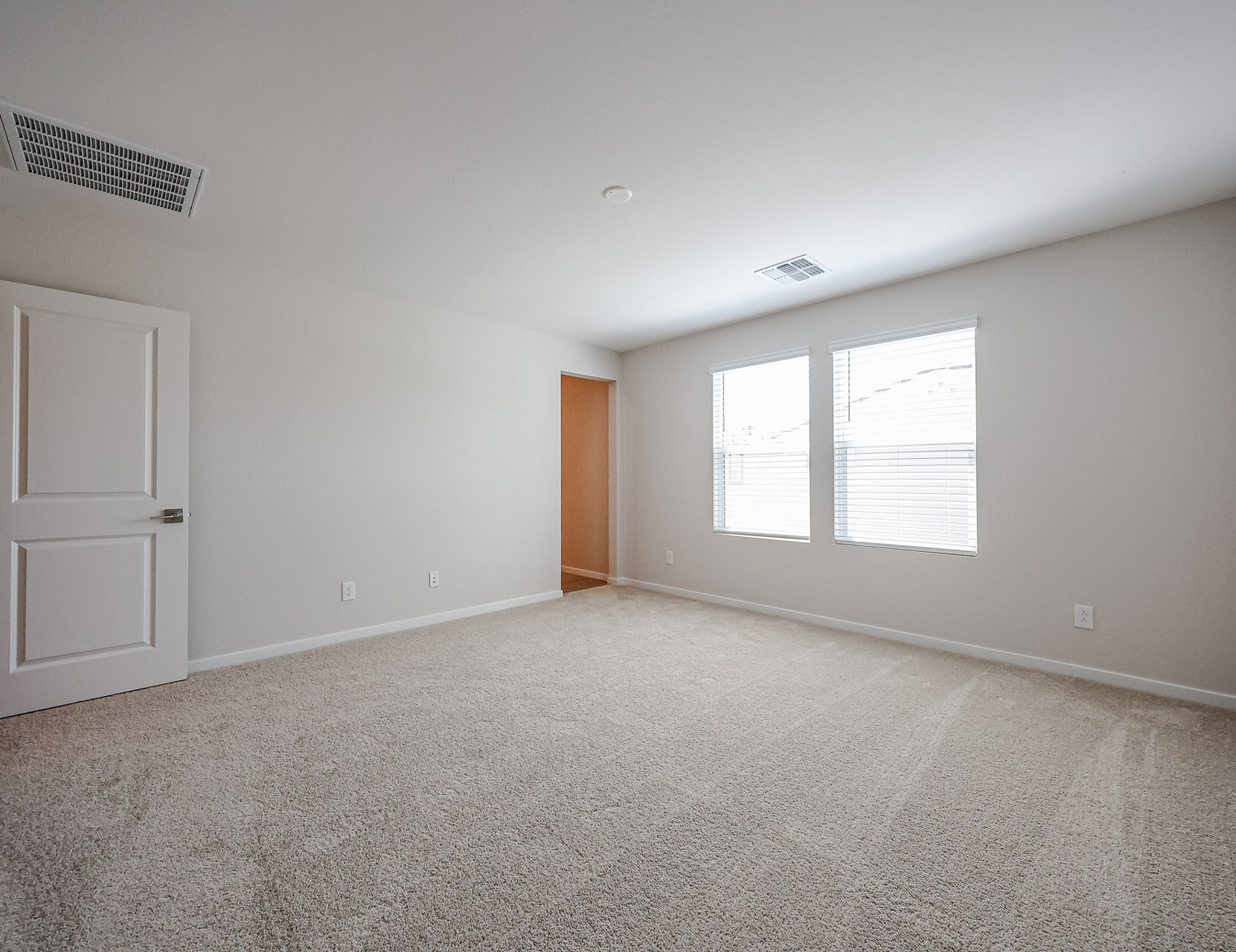 A room with a carpet and a door.