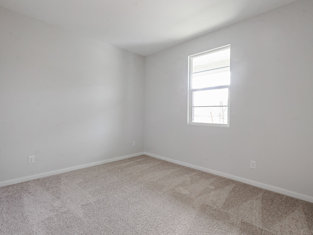 A room with a window and carpet.