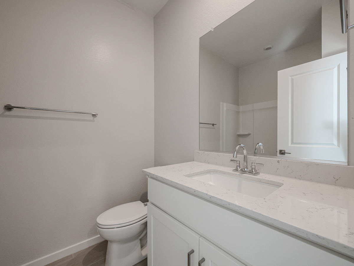 A bathroom with a sink toilet and mirror.