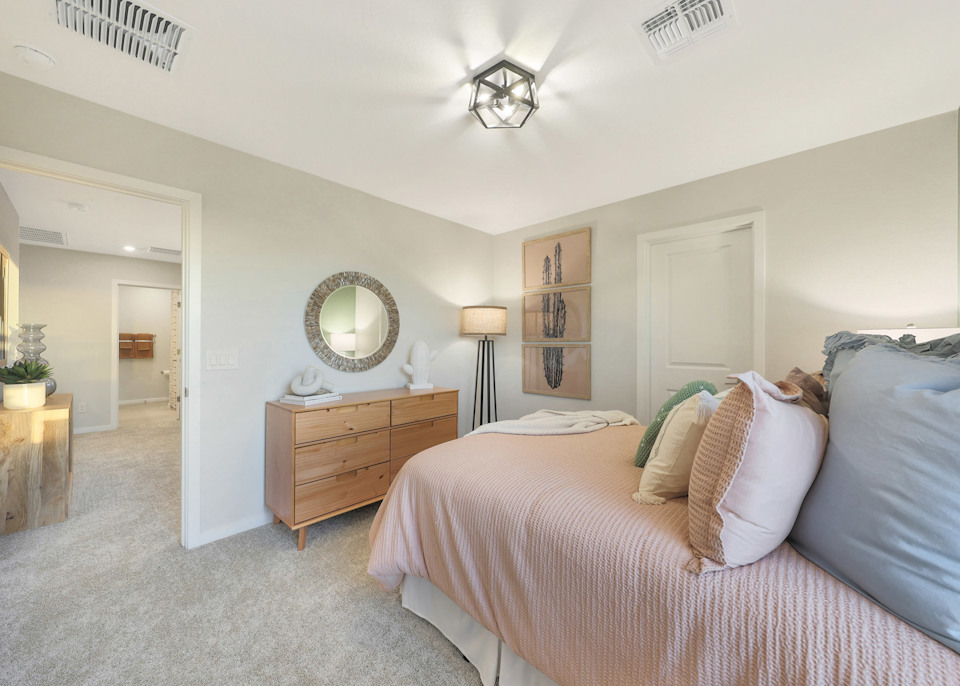 A bedroom with a bed and a mirror.