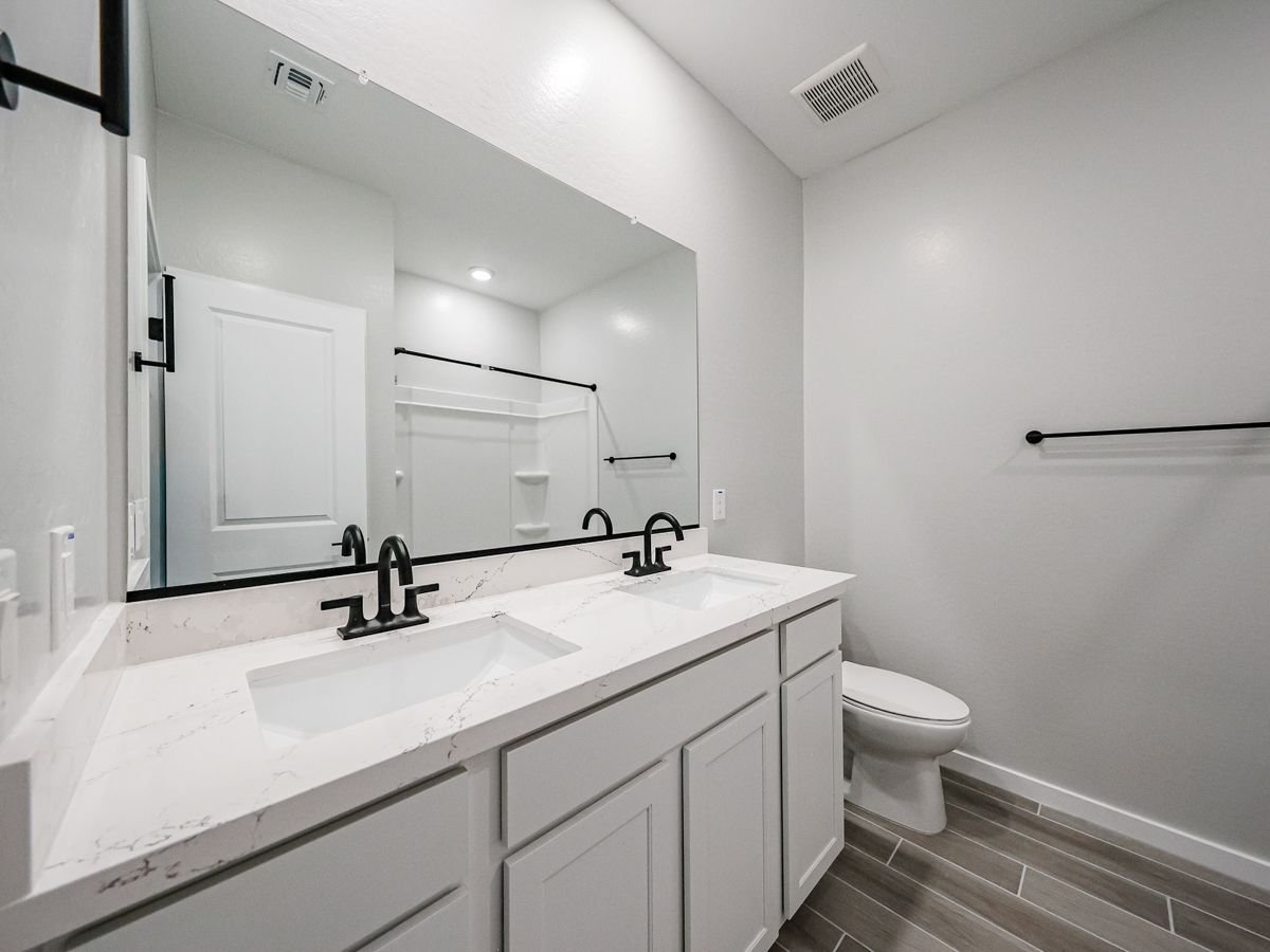 A bathroom with a sink toilet and mirror.