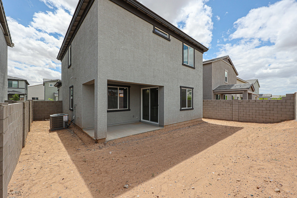 A grey house with a dirt road.