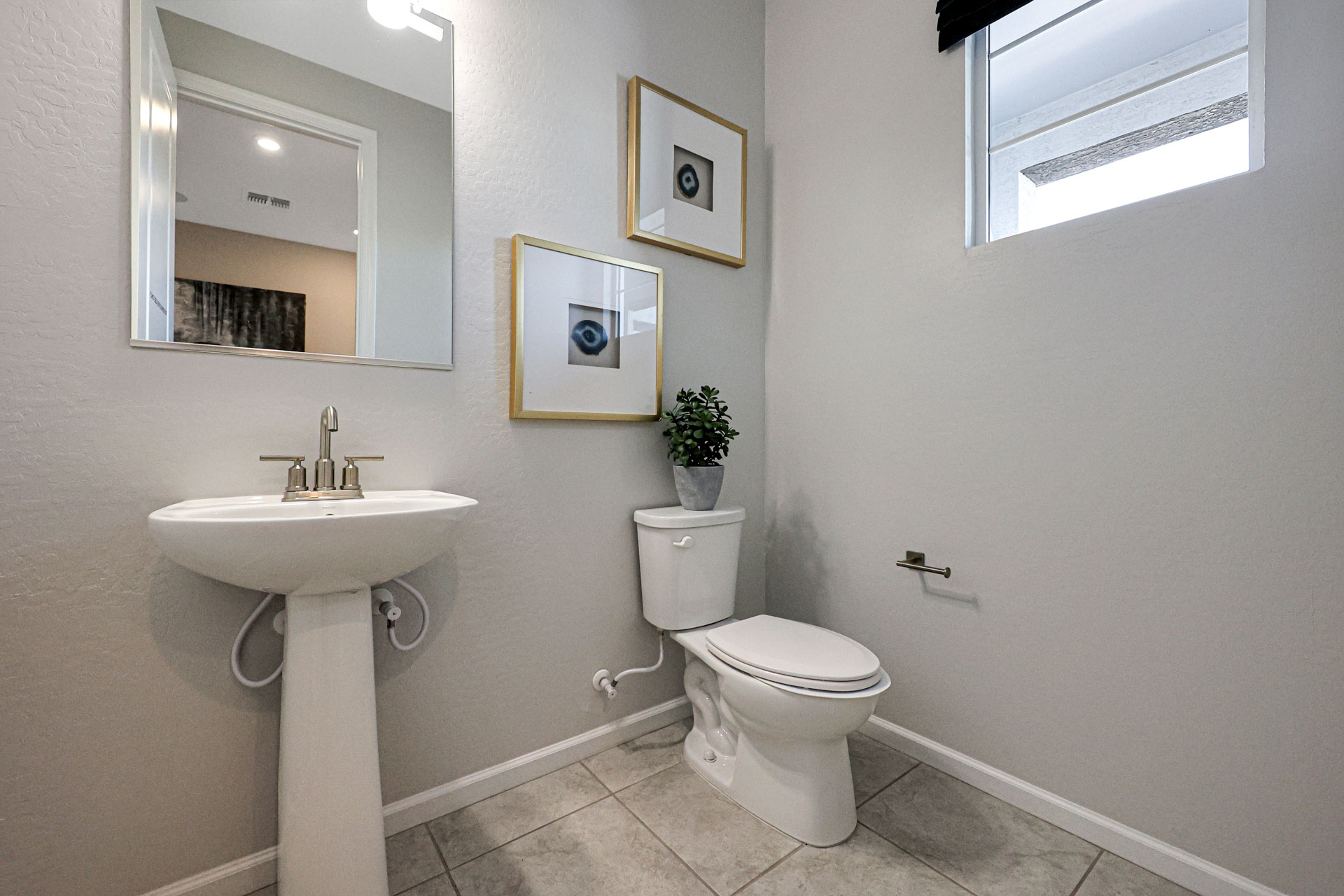 A bathroom with a sink toilet and mirror.