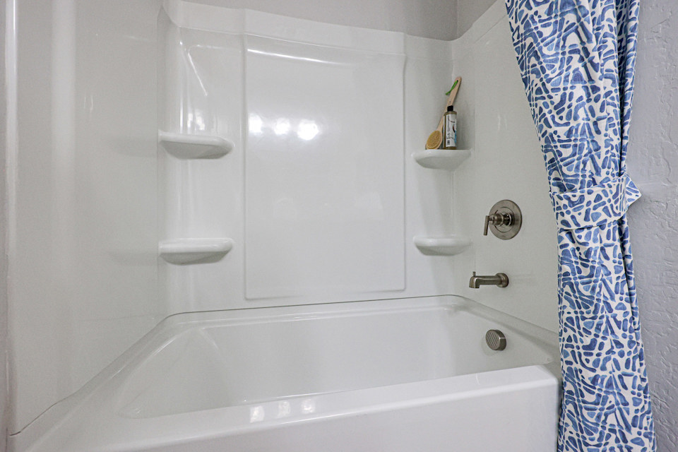 A bathroom with a bathtub and shower curtain.