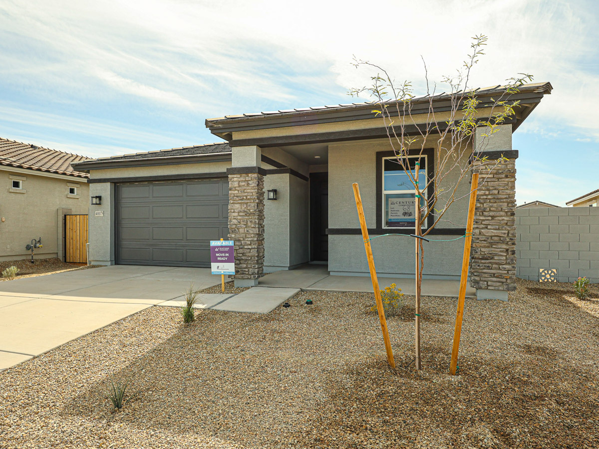 A building with a brick wall and a tree in front of it.