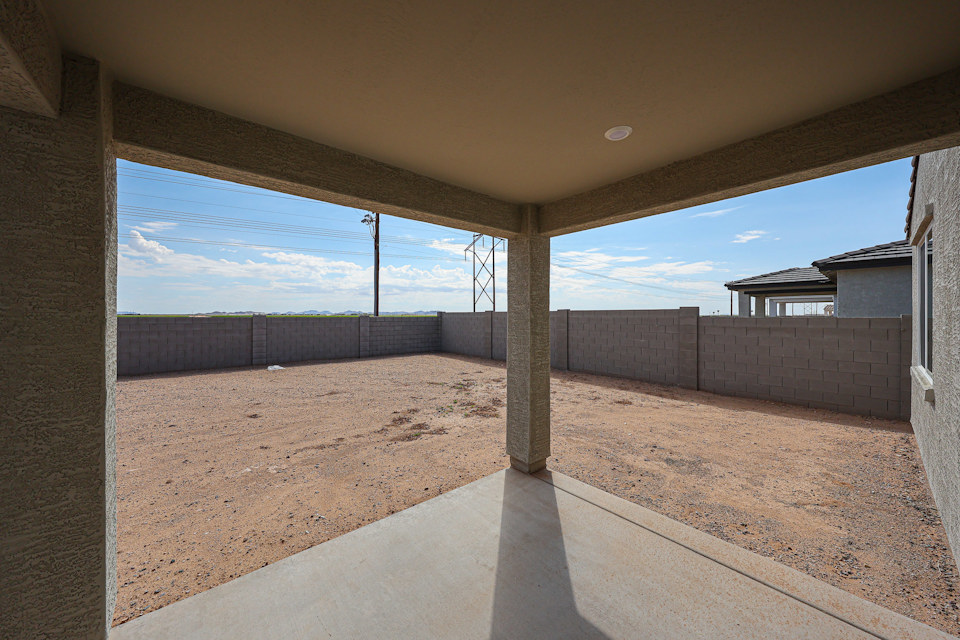 A concrete walkway with a fence and a building in the background.