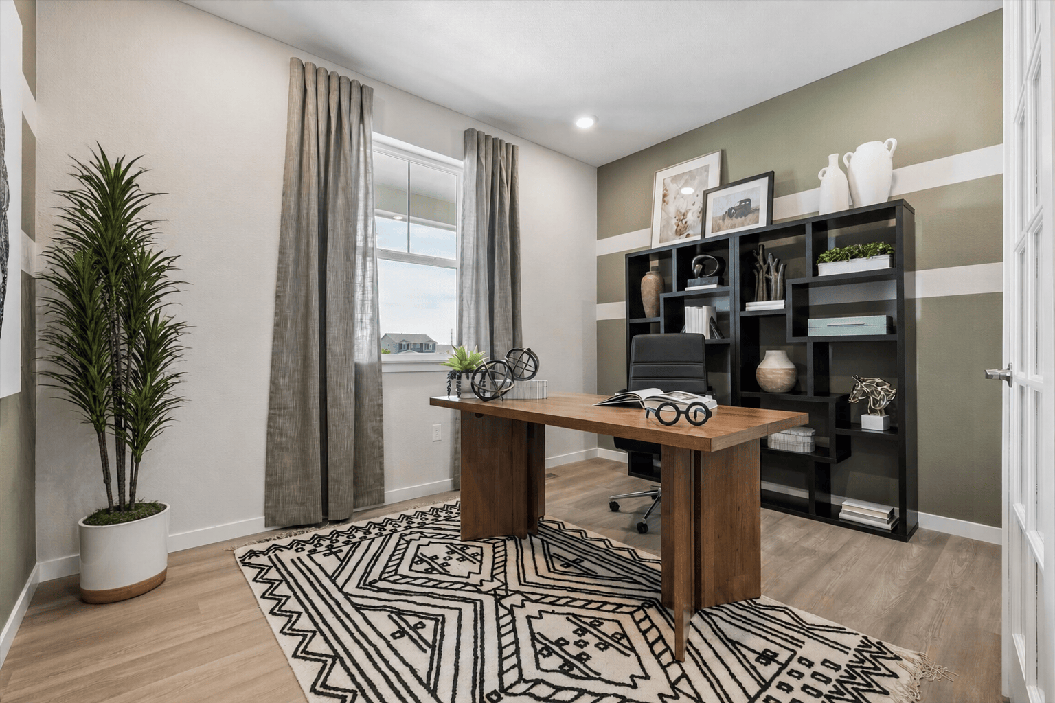 A room with a desk and a shelf with books on it.