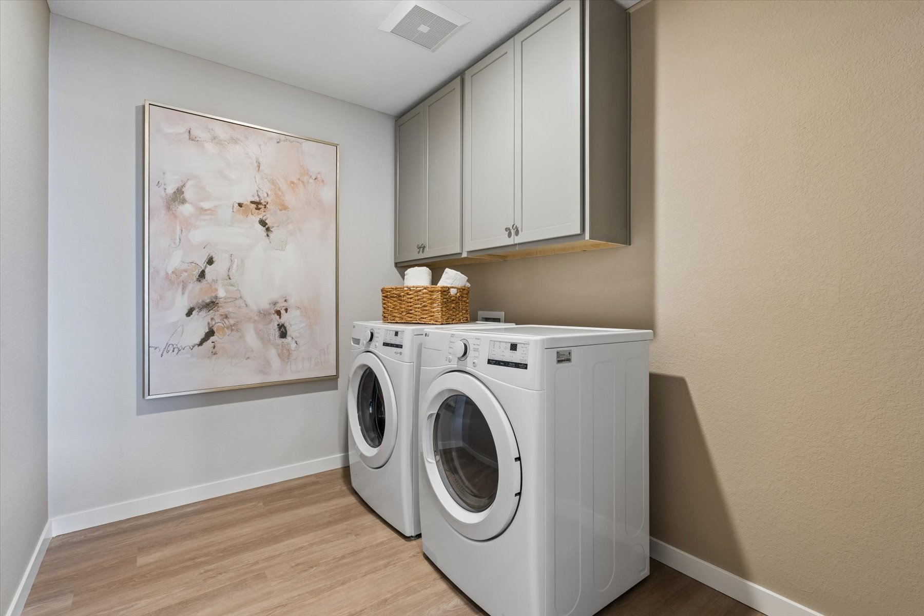 A white laundry room with a white wall and a white laundry basket.