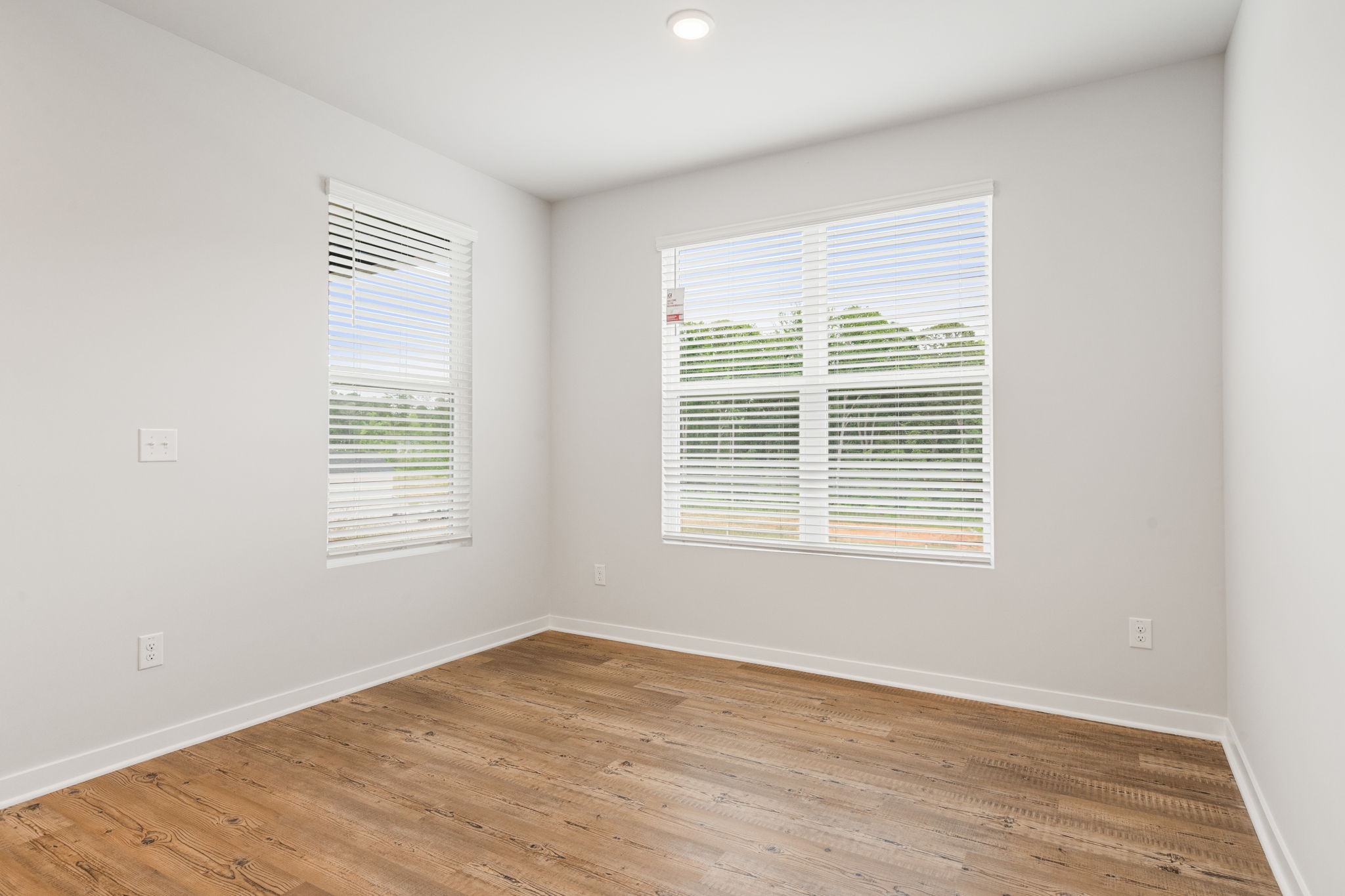 A room with a wood floor and a window with blinds.