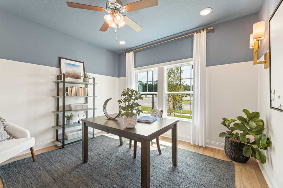 A living room with a table and a fan.