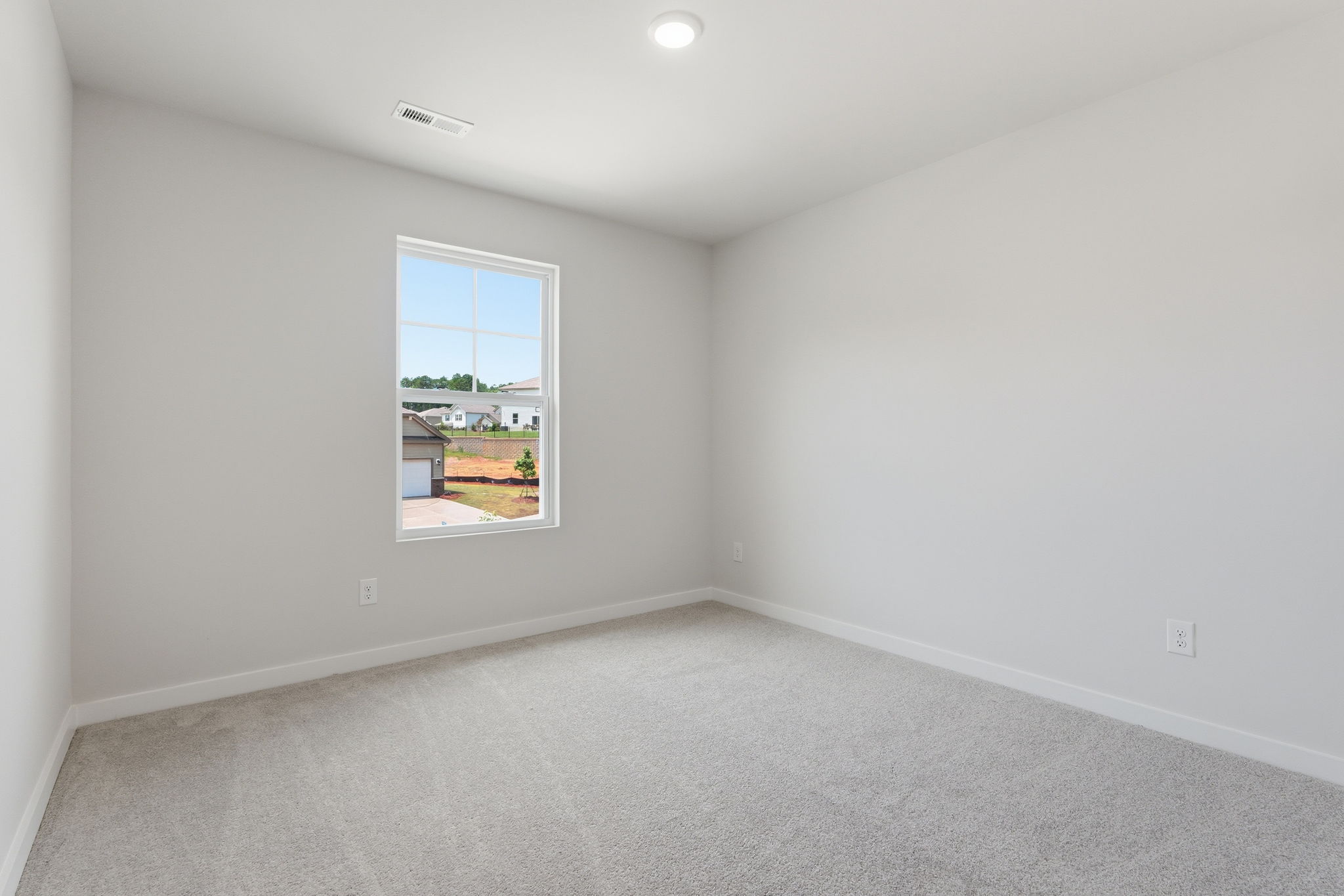A room with a window and a white wall.