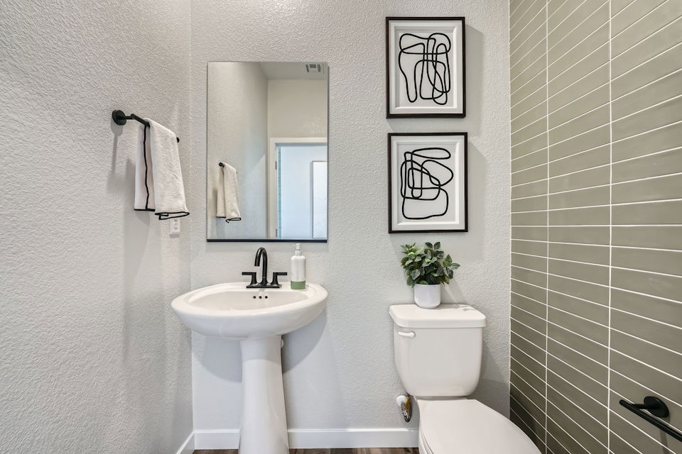 A bathroom with a sink toilet and mirror.