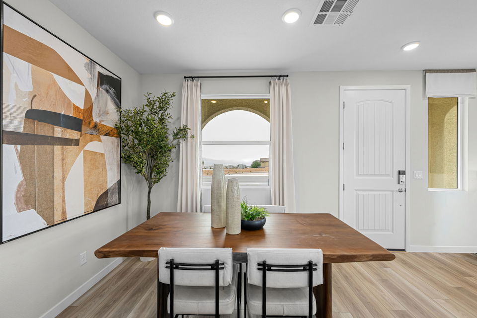 A dining room table with chairs and a painting on the wall.