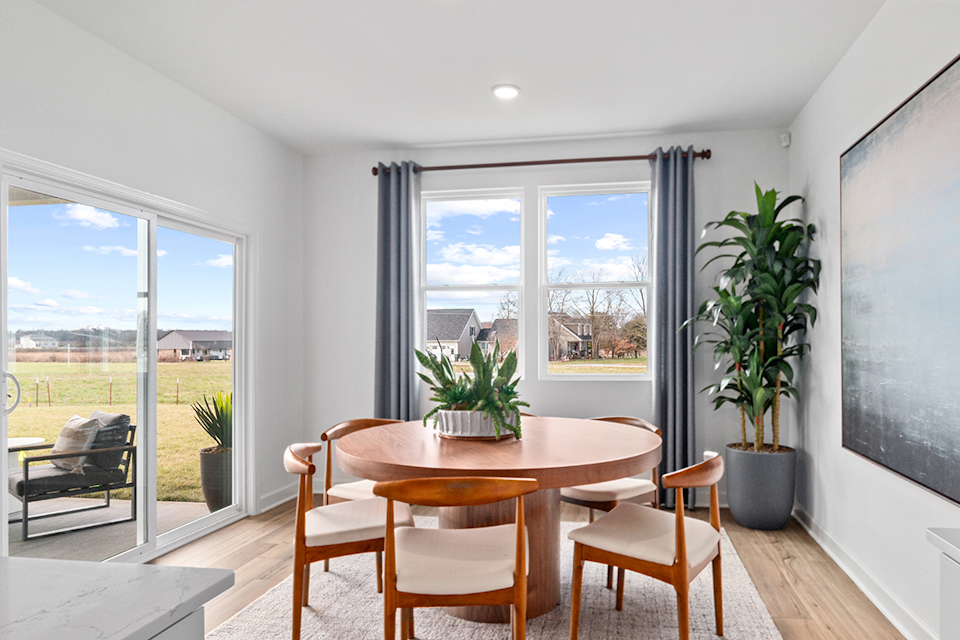 A table and chairs in a room with a window and a view of the water.