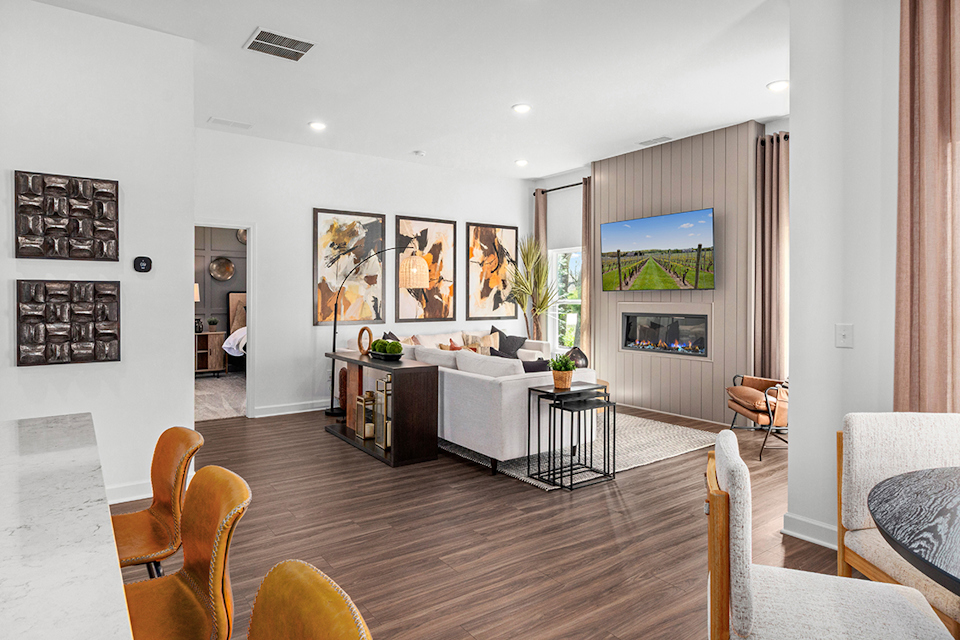 A room with a wood floor and a wood floor with a white couch and a table with chairs.