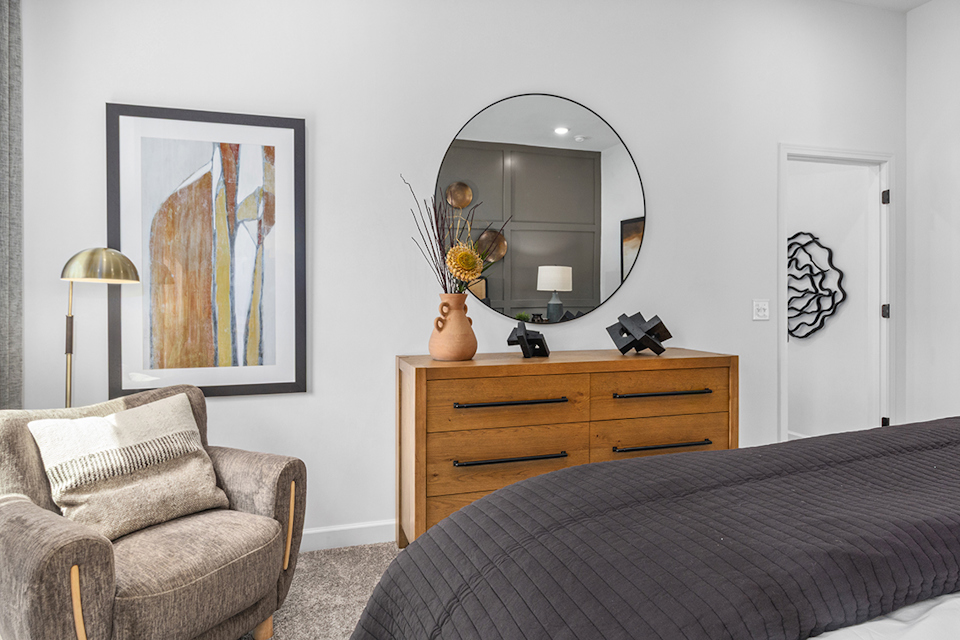 A bedroom with a mirror and a bed.