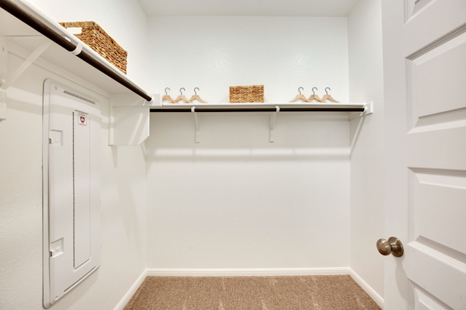 A white room with a shelf and a basket on the wall.