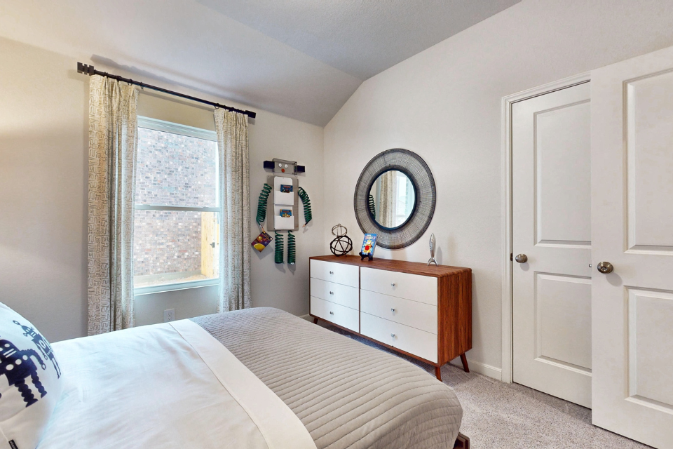 A bedroom with a mirror and a dresser.