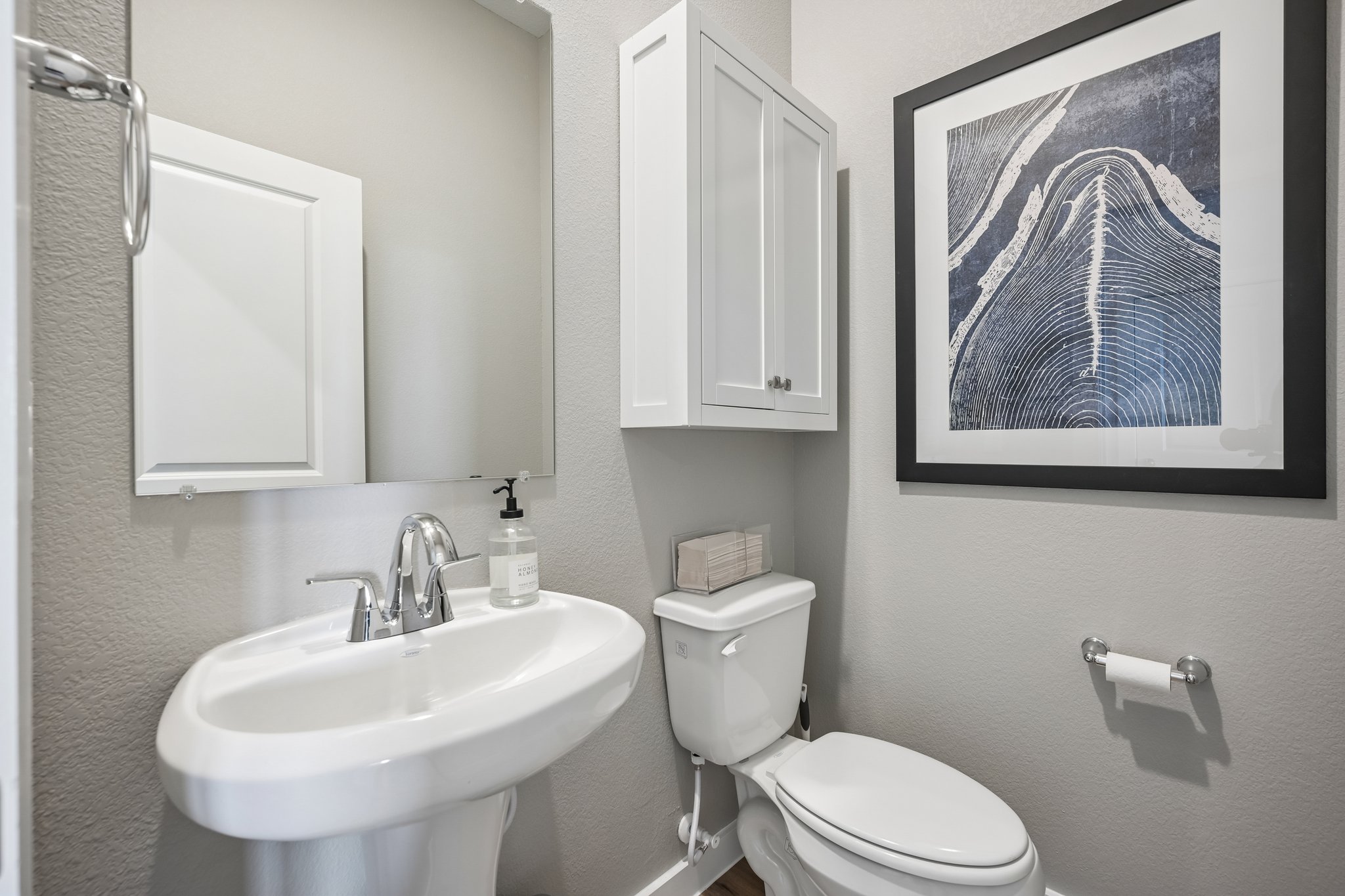 A bathroom with a sink toilet and a painting on the wall.