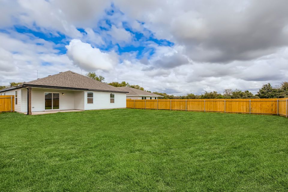 A house with a fence and a field in front of it.