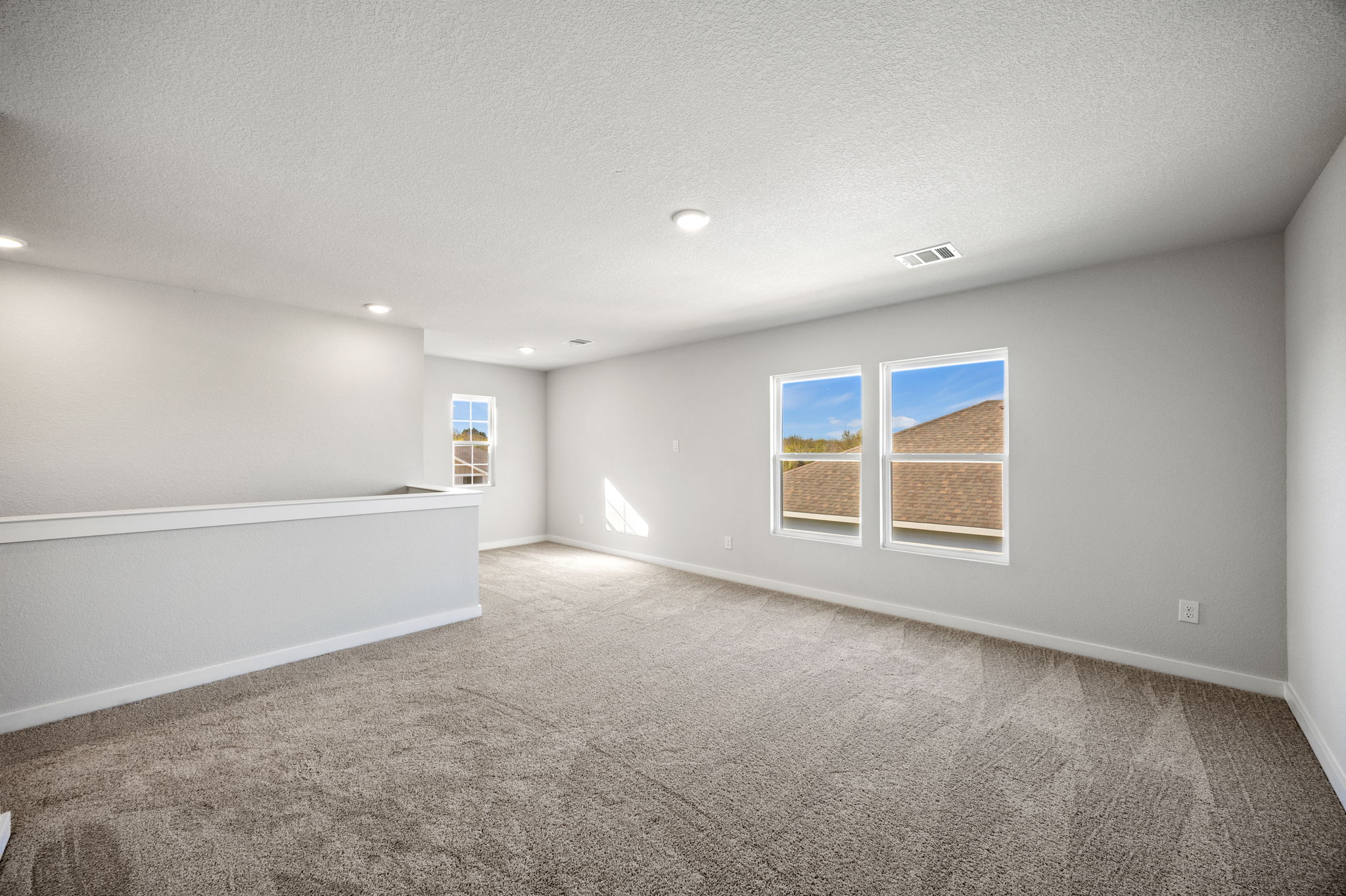 A room with a carpet and a white wall with a window.
