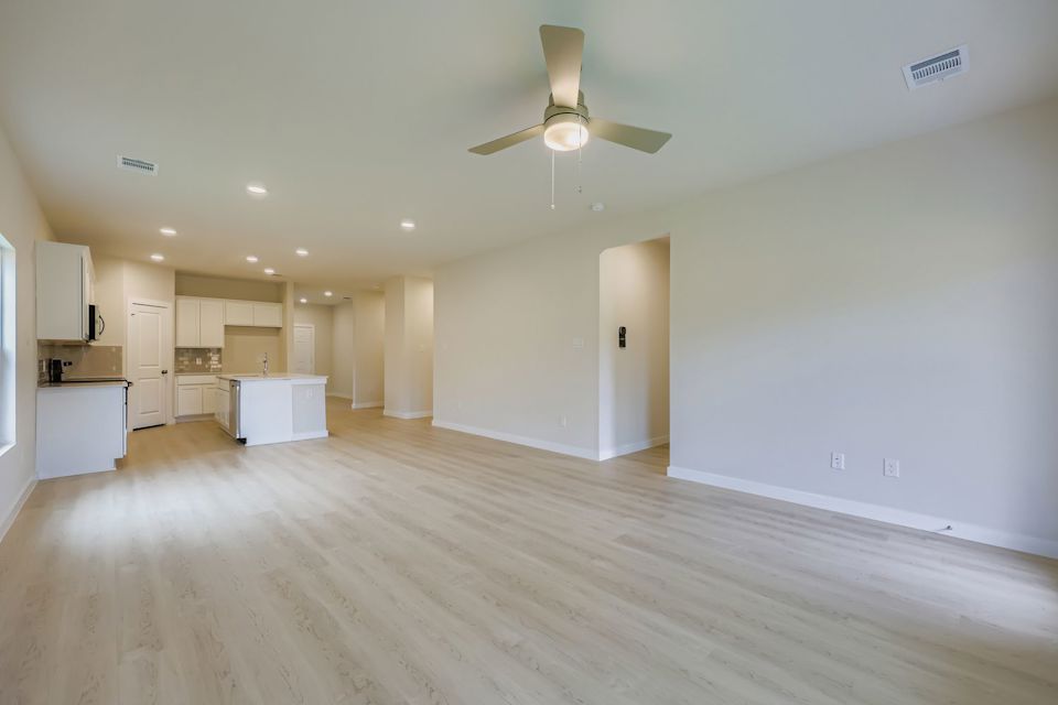 A large empty room with a ceiling fan and a wood floor.