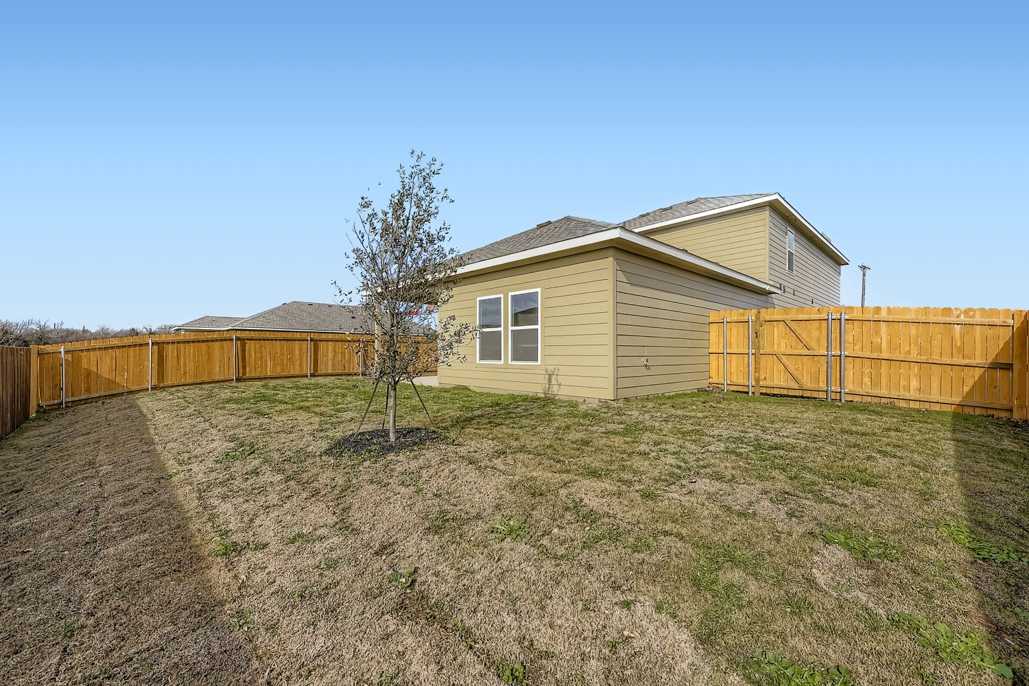 A house with a fence and a tree in the front.