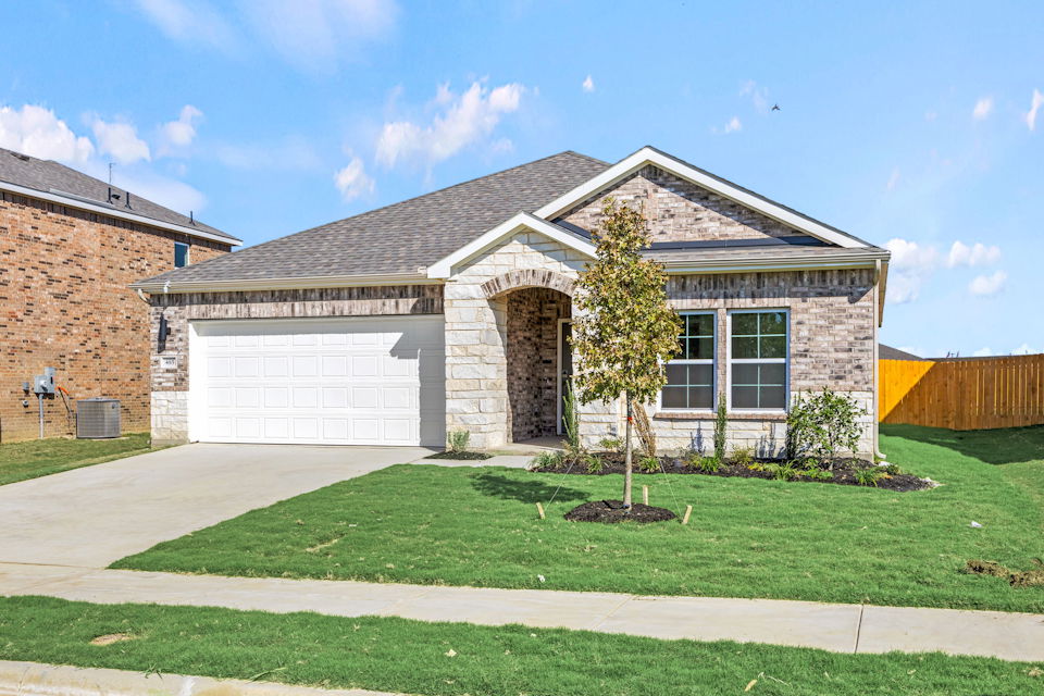A house with a garage and a tree in the front.