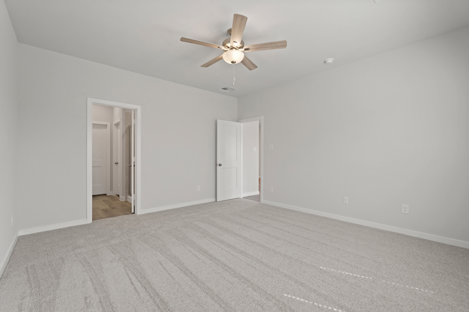 A room with a ceiling fan and white doors.