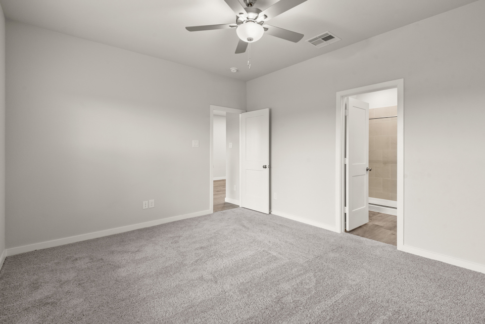 A room with a ceiling fan and a door.