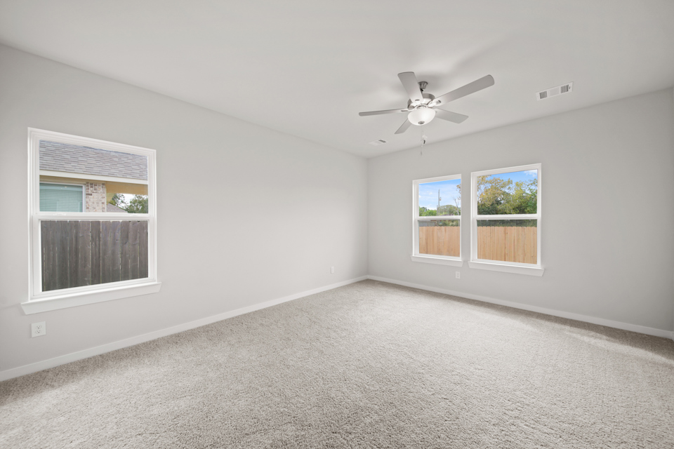 A room with a ceiling fan and windows.