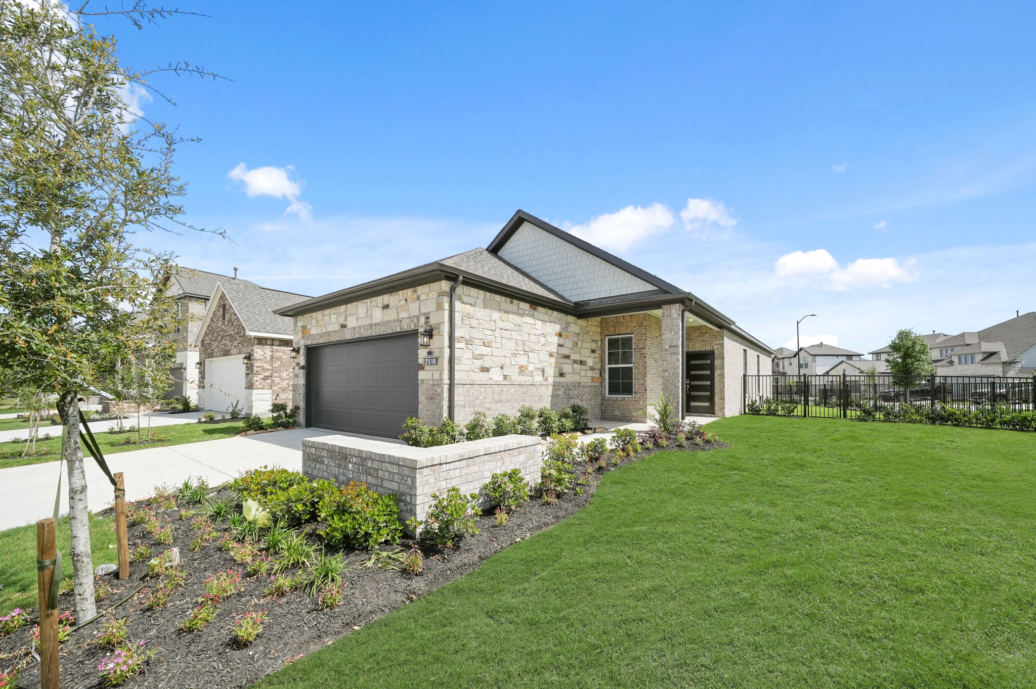 A house with a fence and a yard with a stone wall.