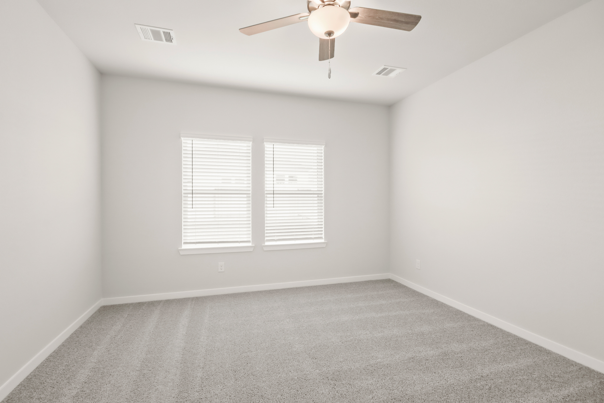 A room with a ceiling fan and a carpet.