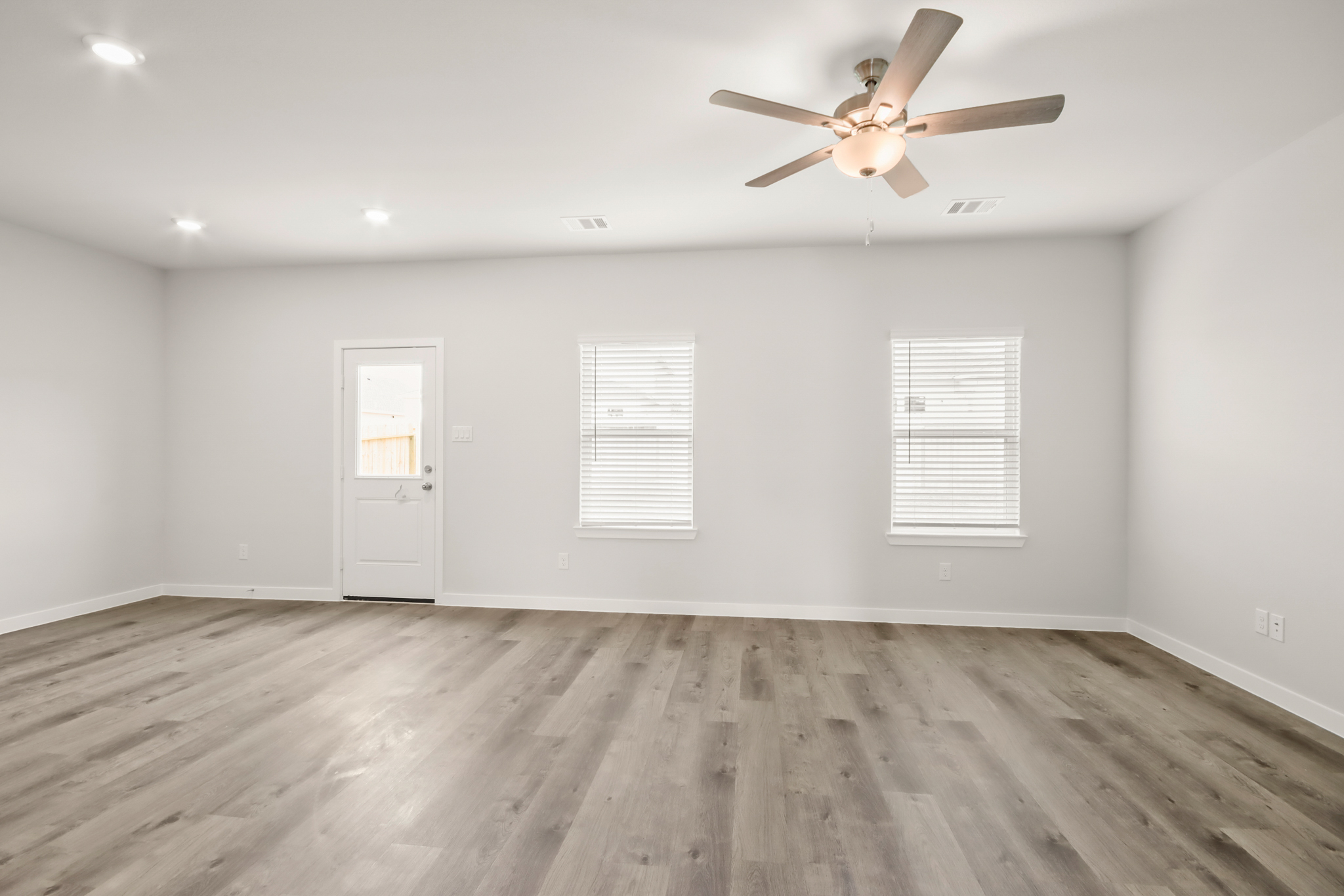 A room with a ceiling fan and a wood floor.