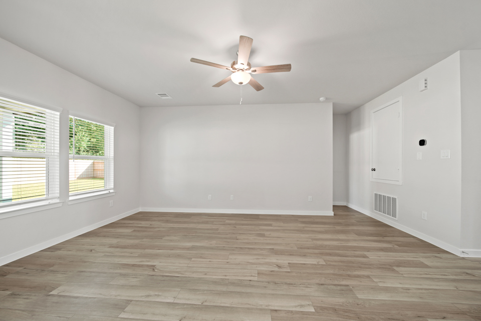 A room with a ceiling fan and a wood floor.