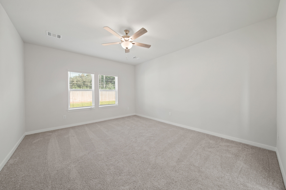 A room with a ceiling fan and a carpet.