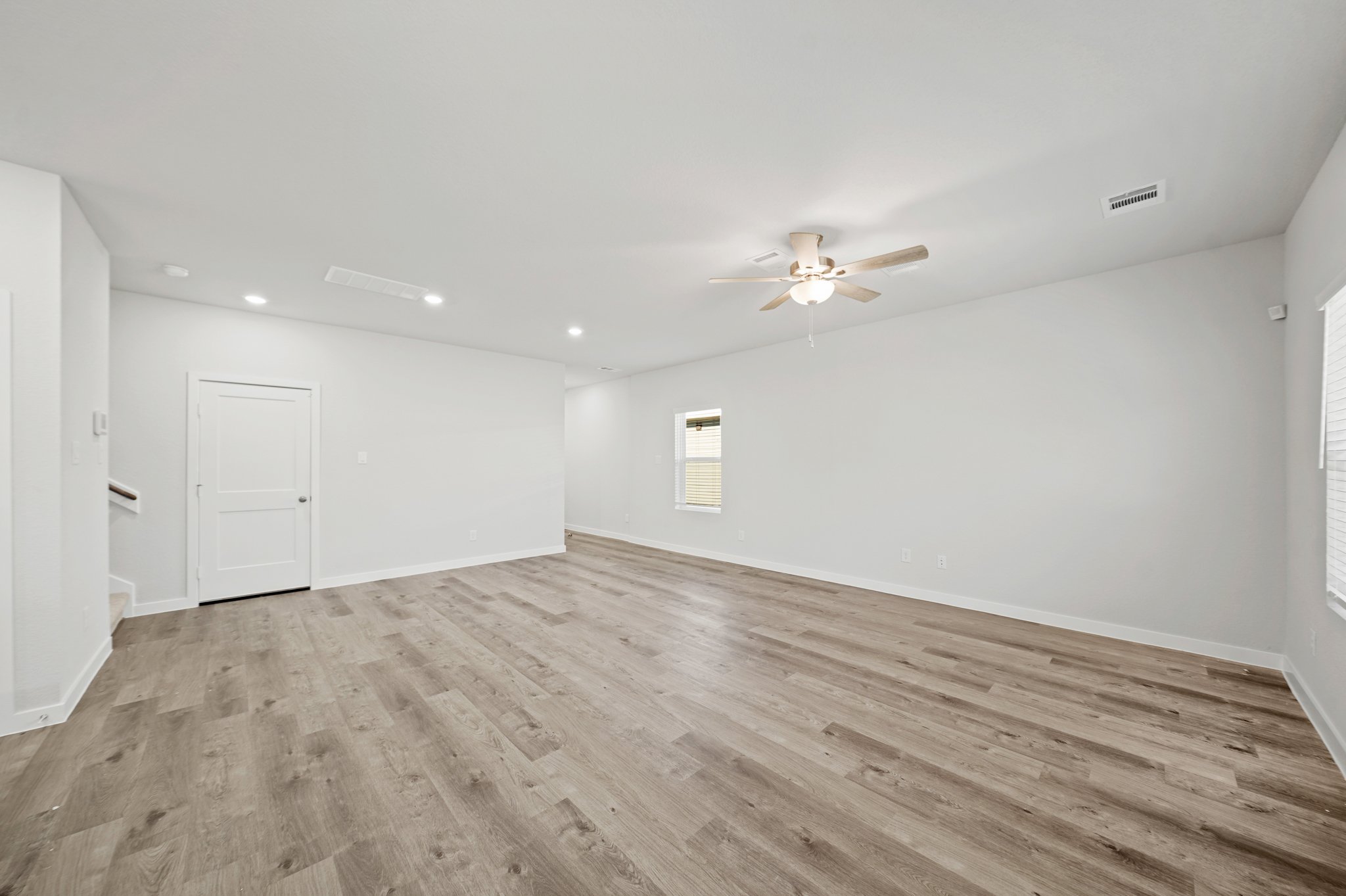 A room with a wood floor and a ceiling fan.