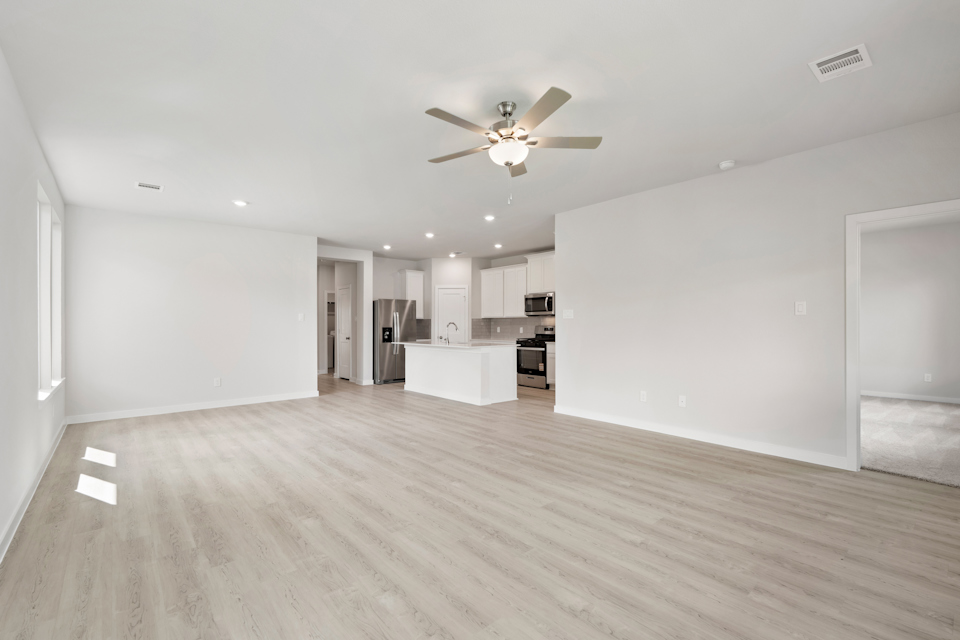 A large empty room with a ceiling fan and a wood floor.