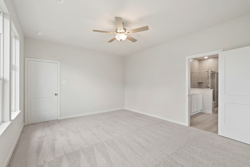A room with a ceiling fan and white walls.