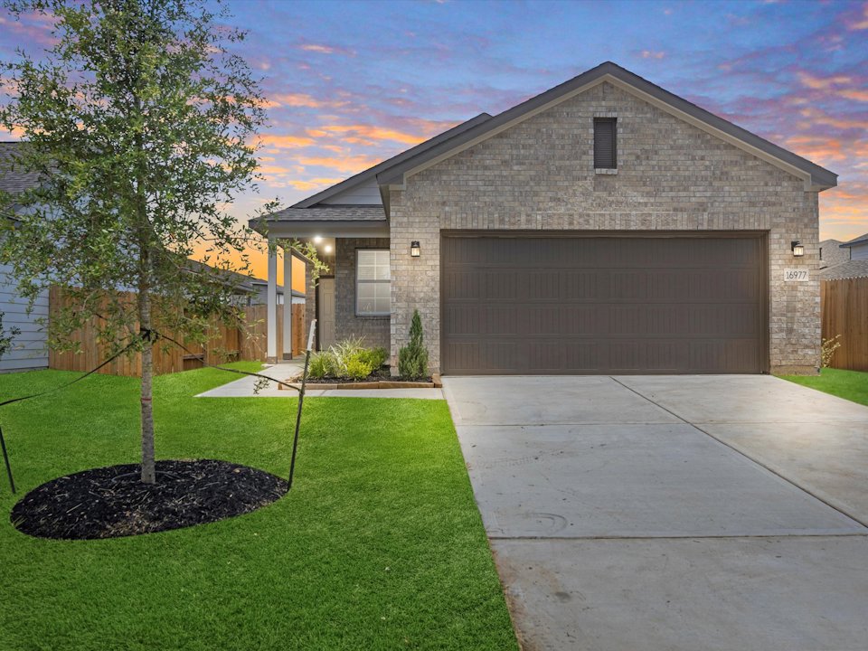 A house with a driveway and a tree in the front.
