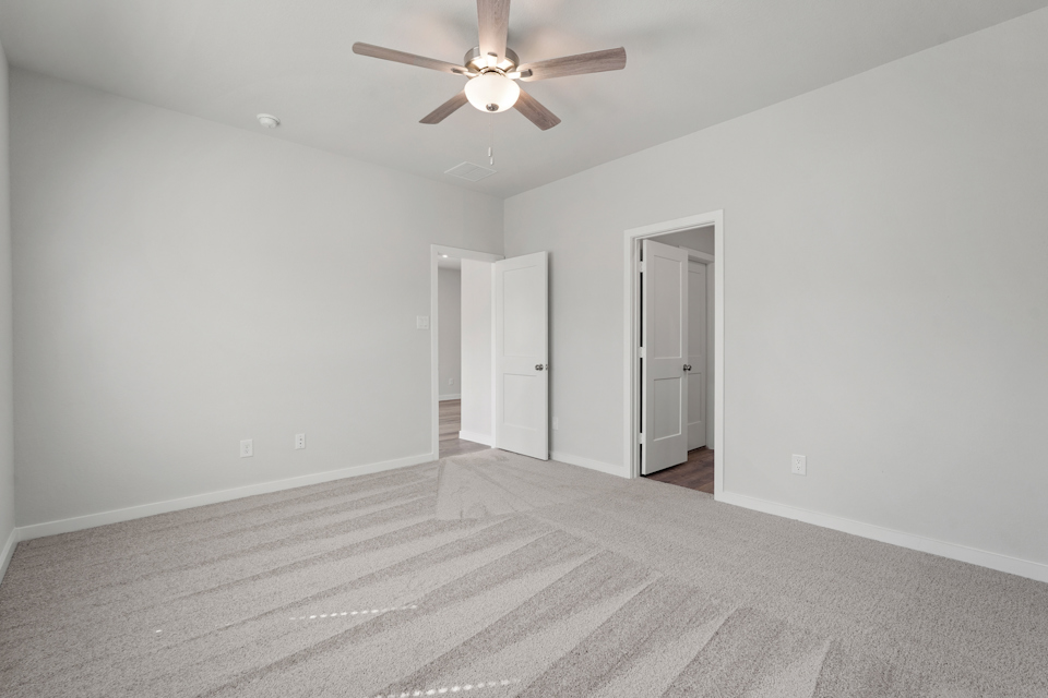 A room with a ceiling fan and a carpet.