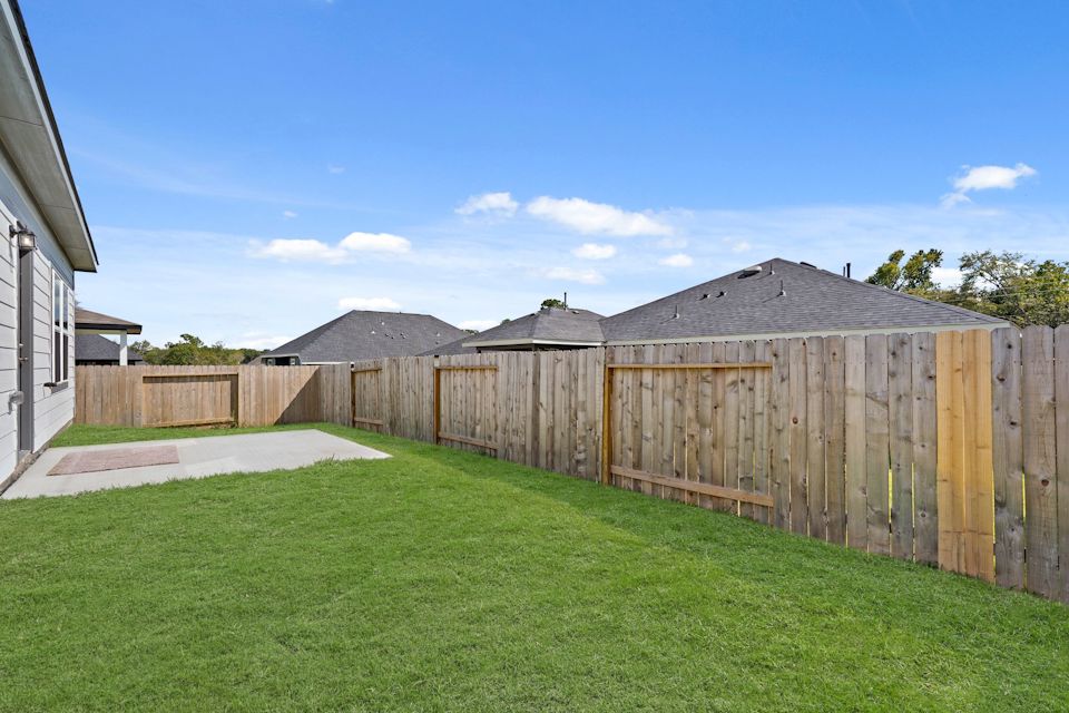 A fenced in yard with a house in the background.
