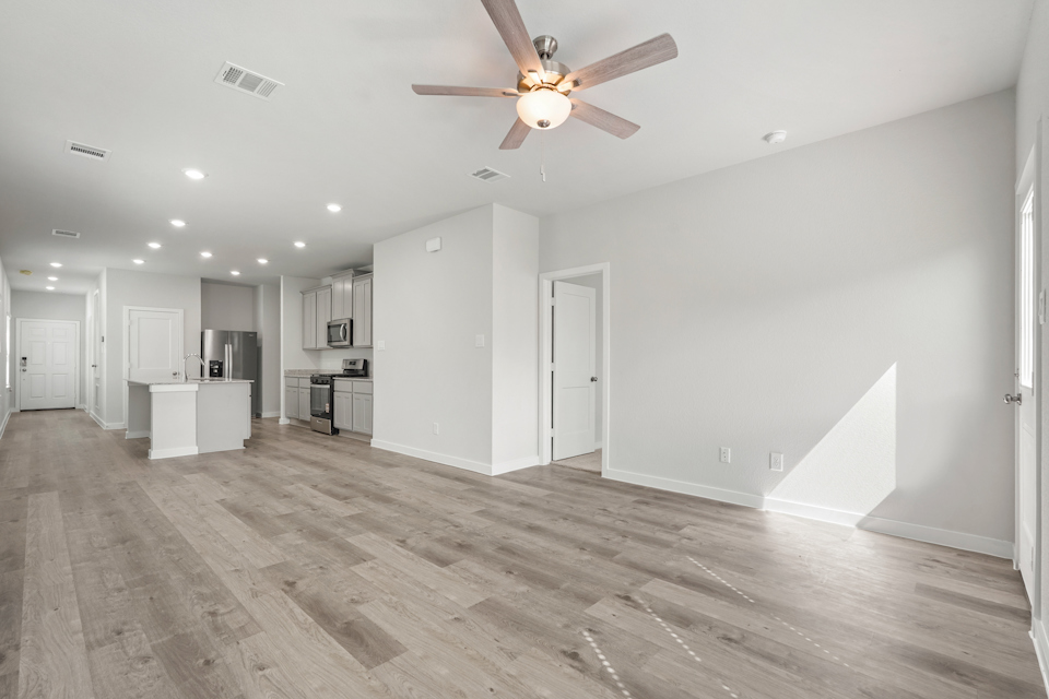 A large empty room with a ceiling fan and a wood floor.