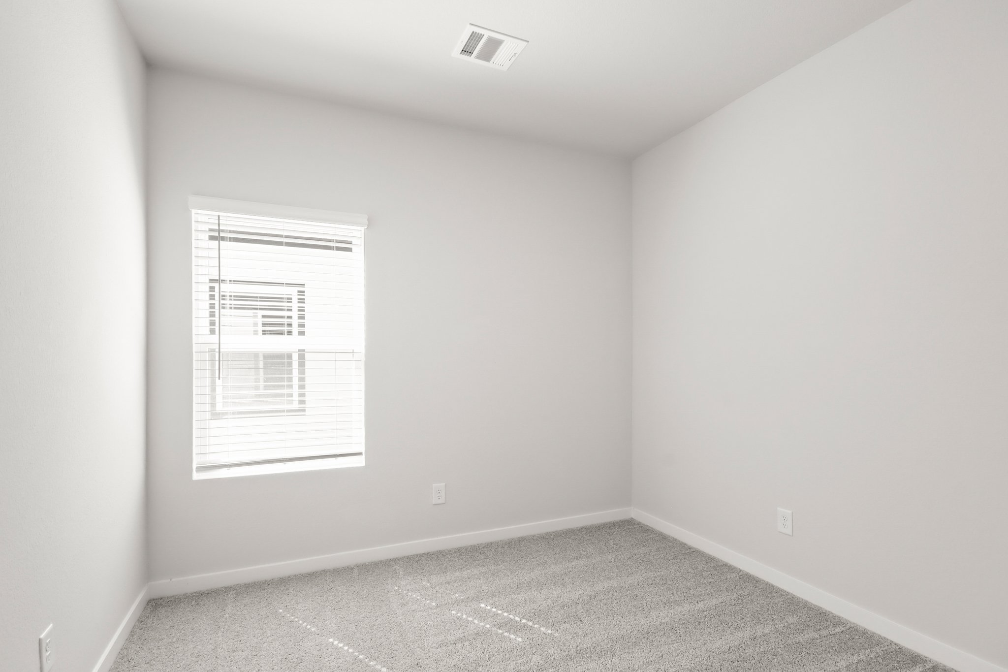 A room with a white wall and a window.