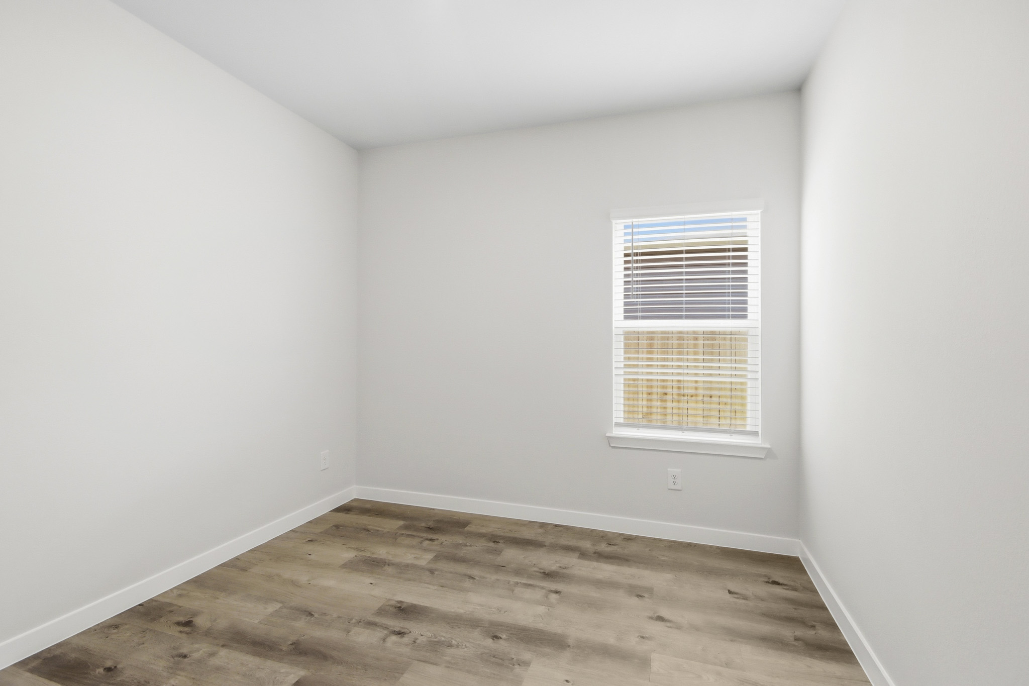 A room with a window and a wood floor.